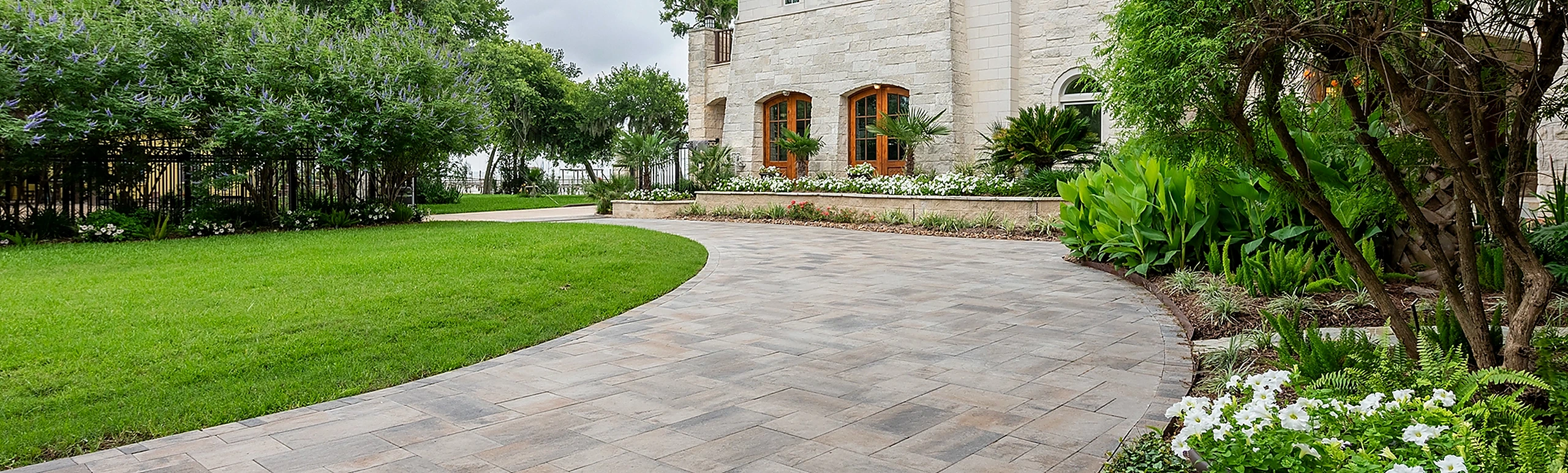 High-strength interlocking paver driveway with custom border stones and estate landscaping